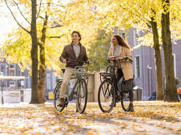 Een man en een vrouw fietsen door de straat. Klik op de afbeelding voor alle stadsfietsen.