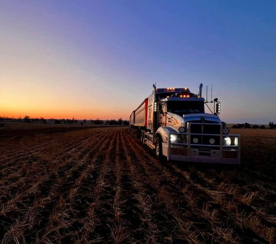 A Semi Truck Is Driving Through A Field At Sunset — BJC Transport In Wondai, QLD