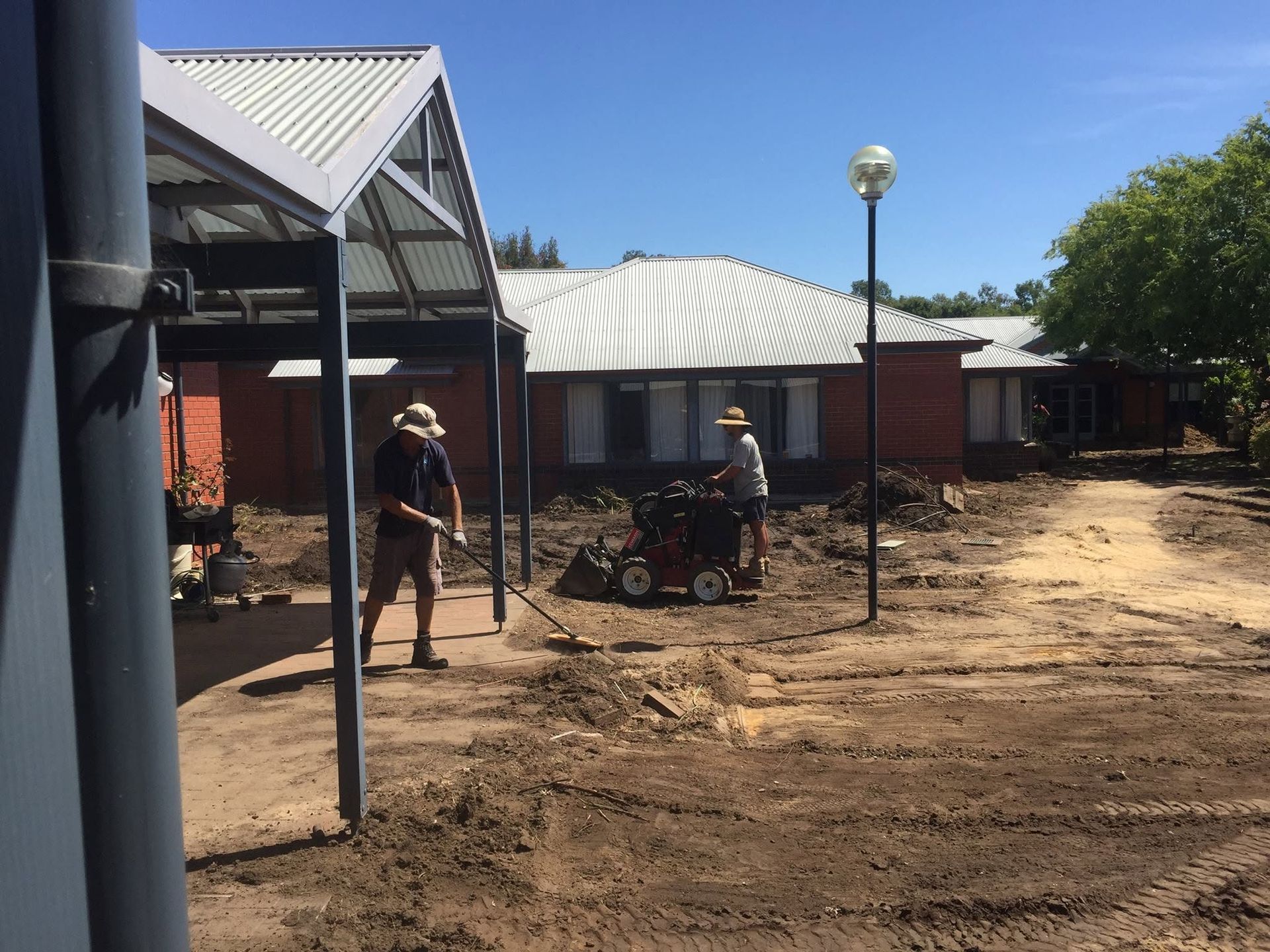 Workers with wheelbarrows near a row of buildings on a dusty construction site under a clear sky Workers with wheelbarrows near a row of buildings on a dusty construction site under a clear sky