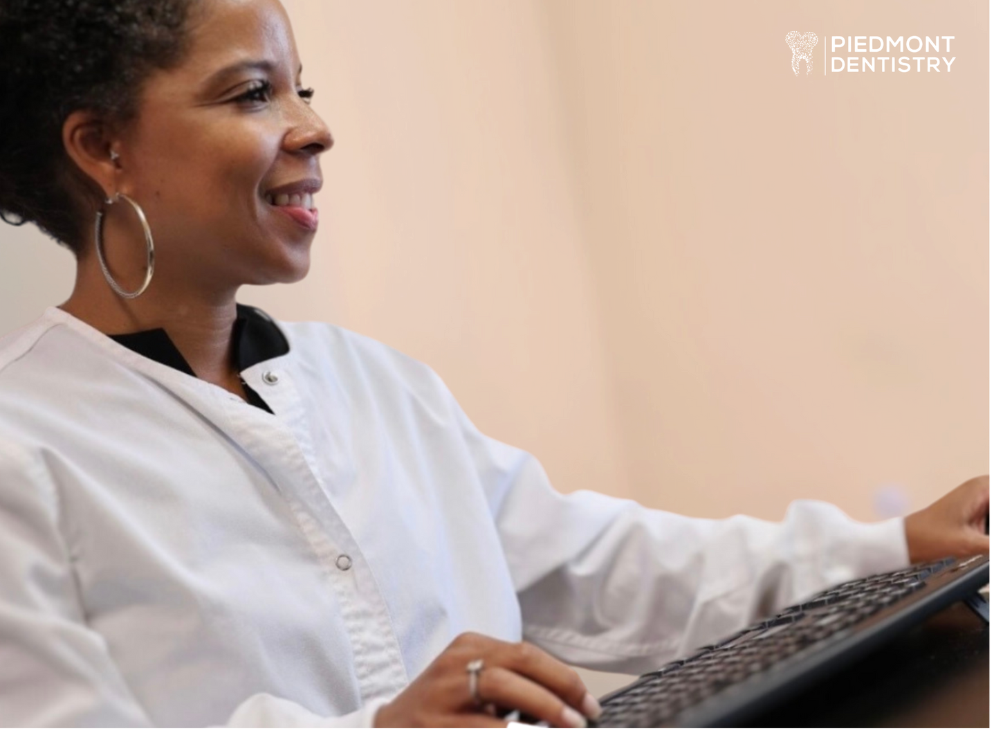 Dr. Gabrielle Williams smiling while typing on her computer in her office. 