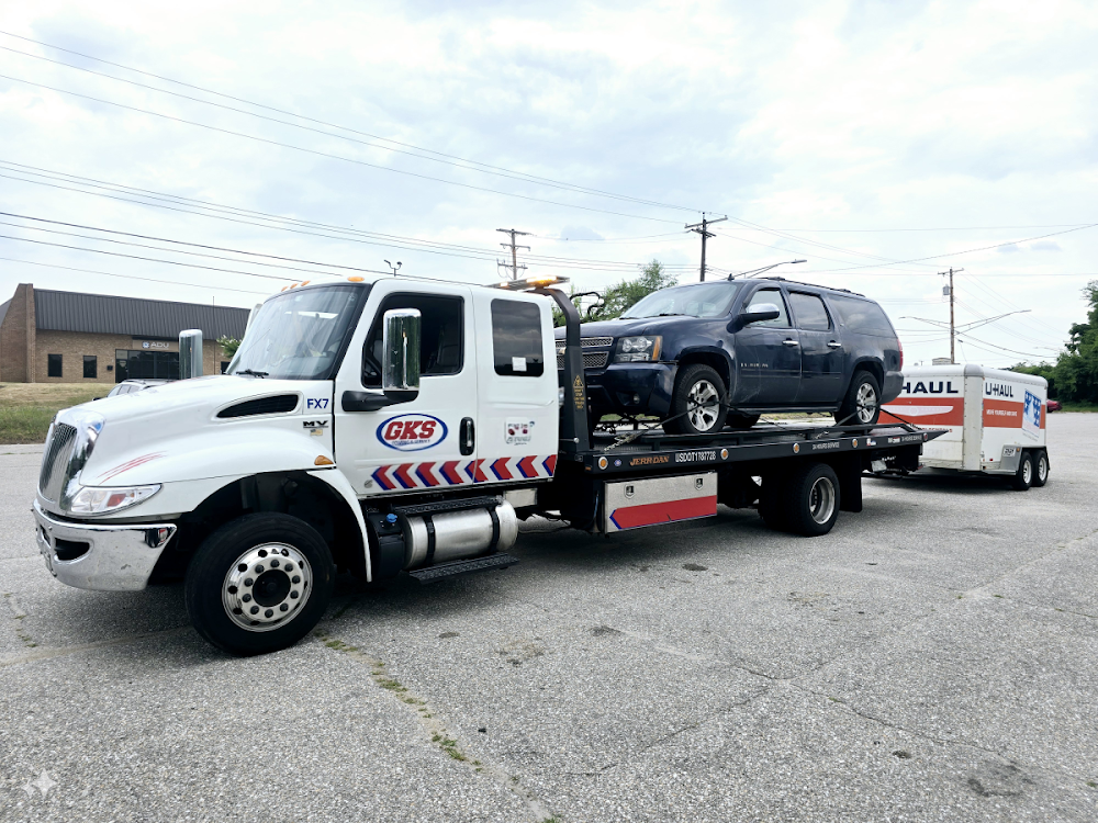A tow truck is towing a suv on a trailer.