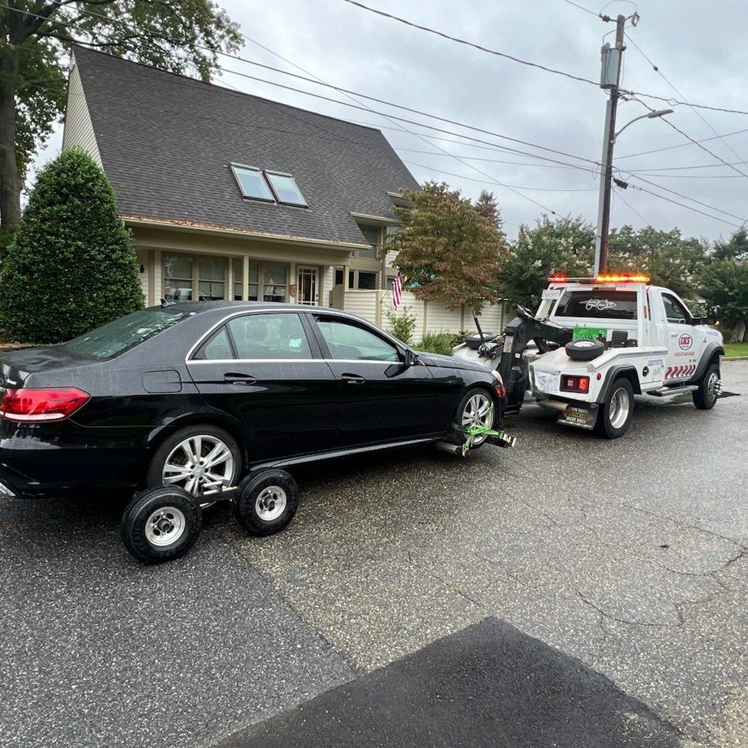 A black car is being towed by a tow truck.