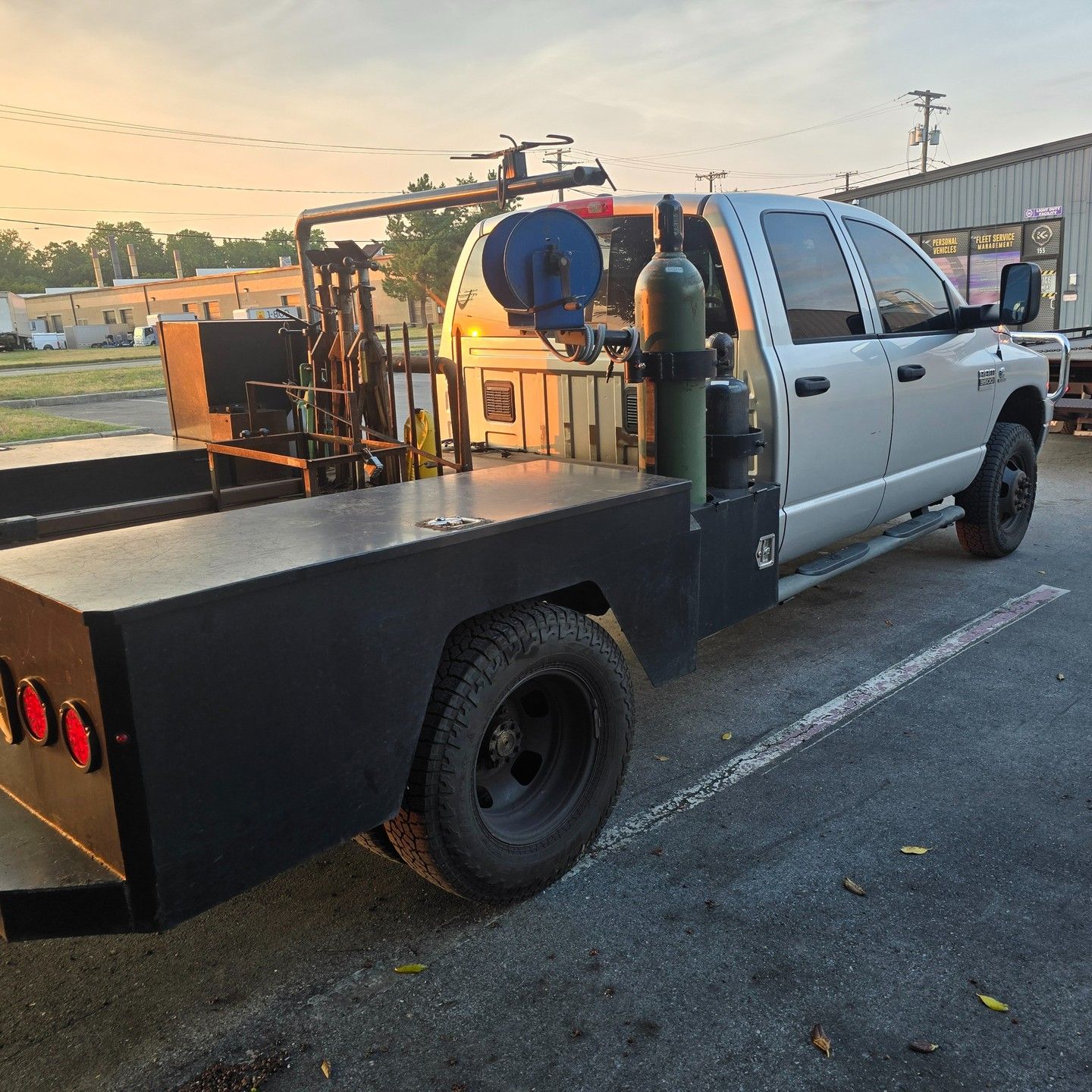 A silver truck with a black bed is parked in a parking lot