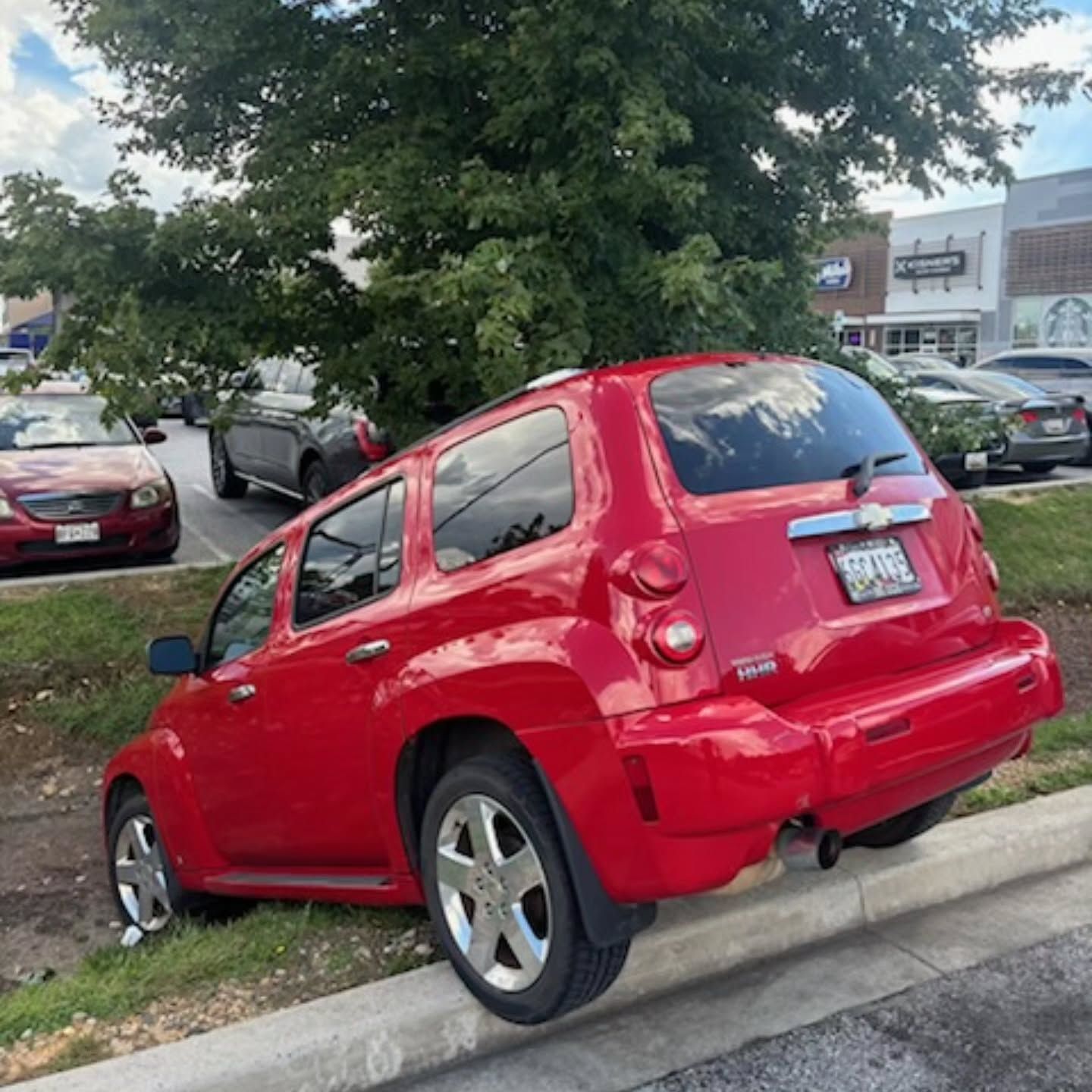 A red car is parked on the side of the road