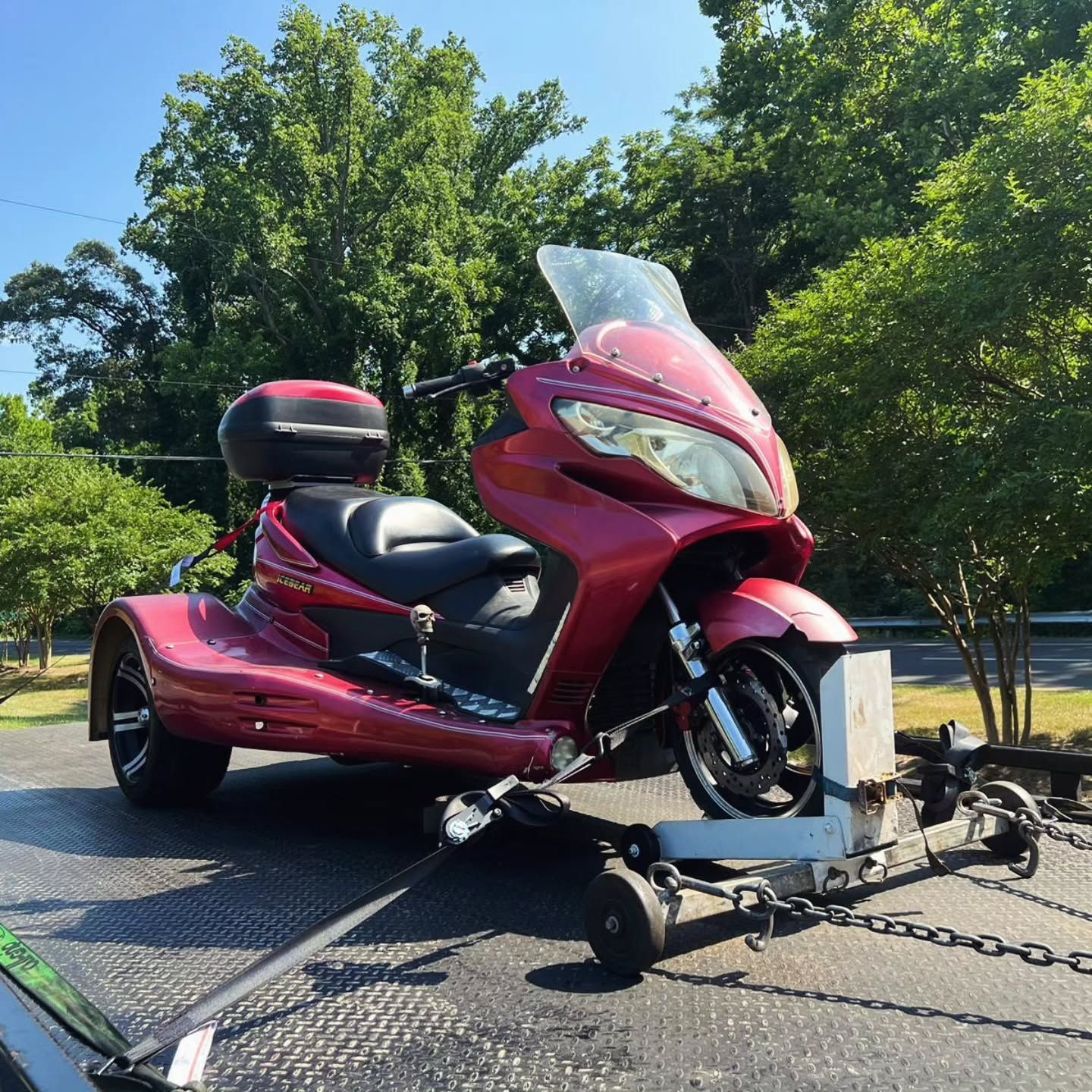 A red motorcycle is being towed by a trailer