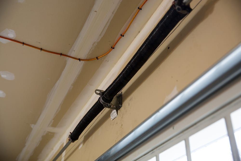 A close up of a garage door spring hanging from the ceiling.