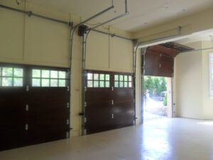 A garage with two garage doors open and a ceiling fan.