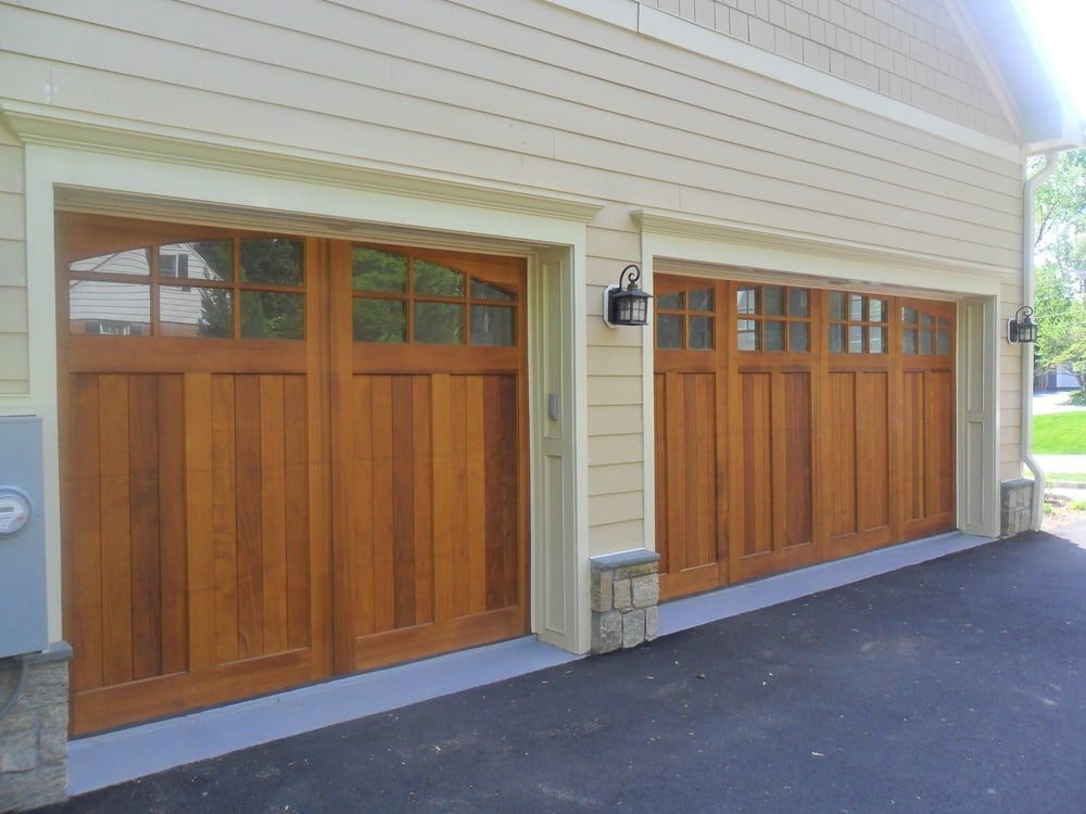 Two wooden garage doors on the side of a house