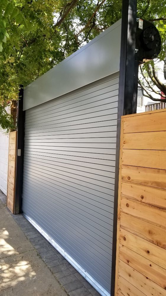 A garage door with a wooden fence behind it.