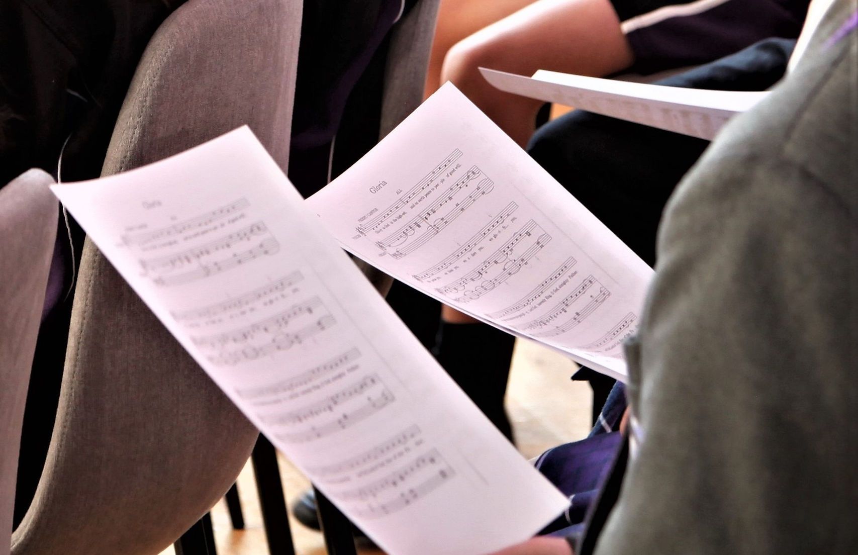 People holding printed music sheets in a rehearsal setting