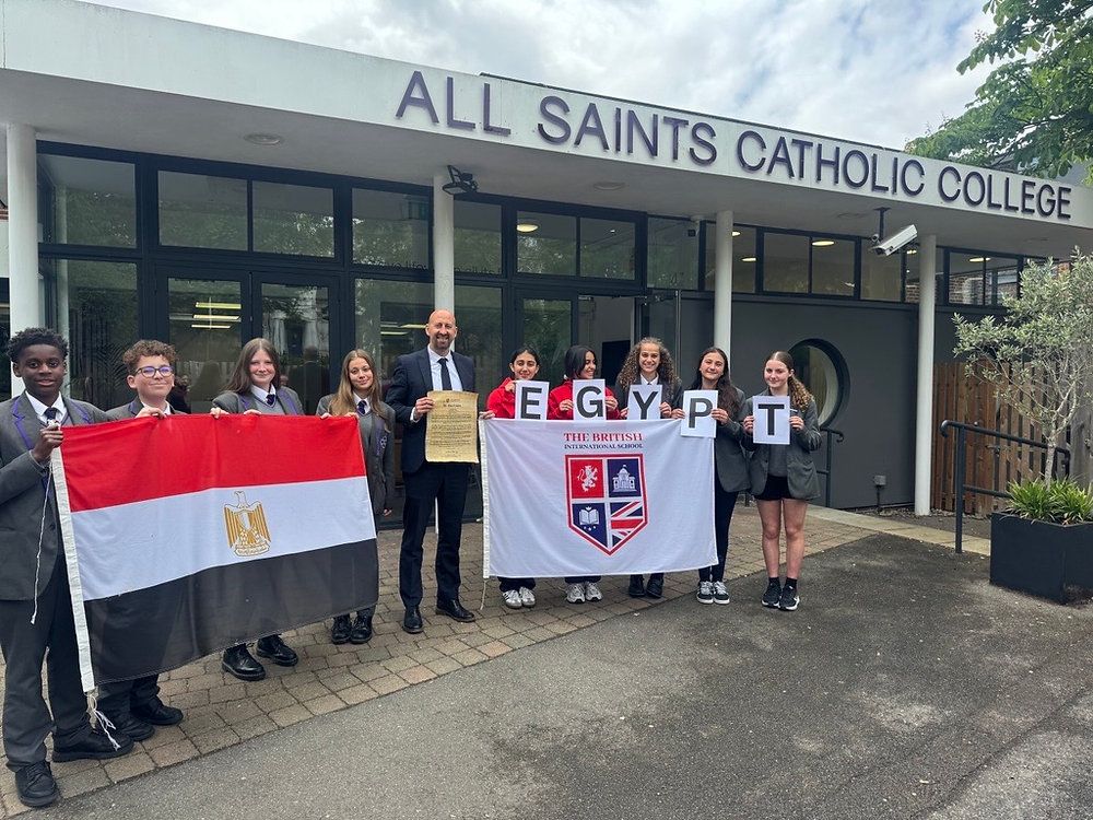 Students holding flags outside All Saints Catholic College entrance