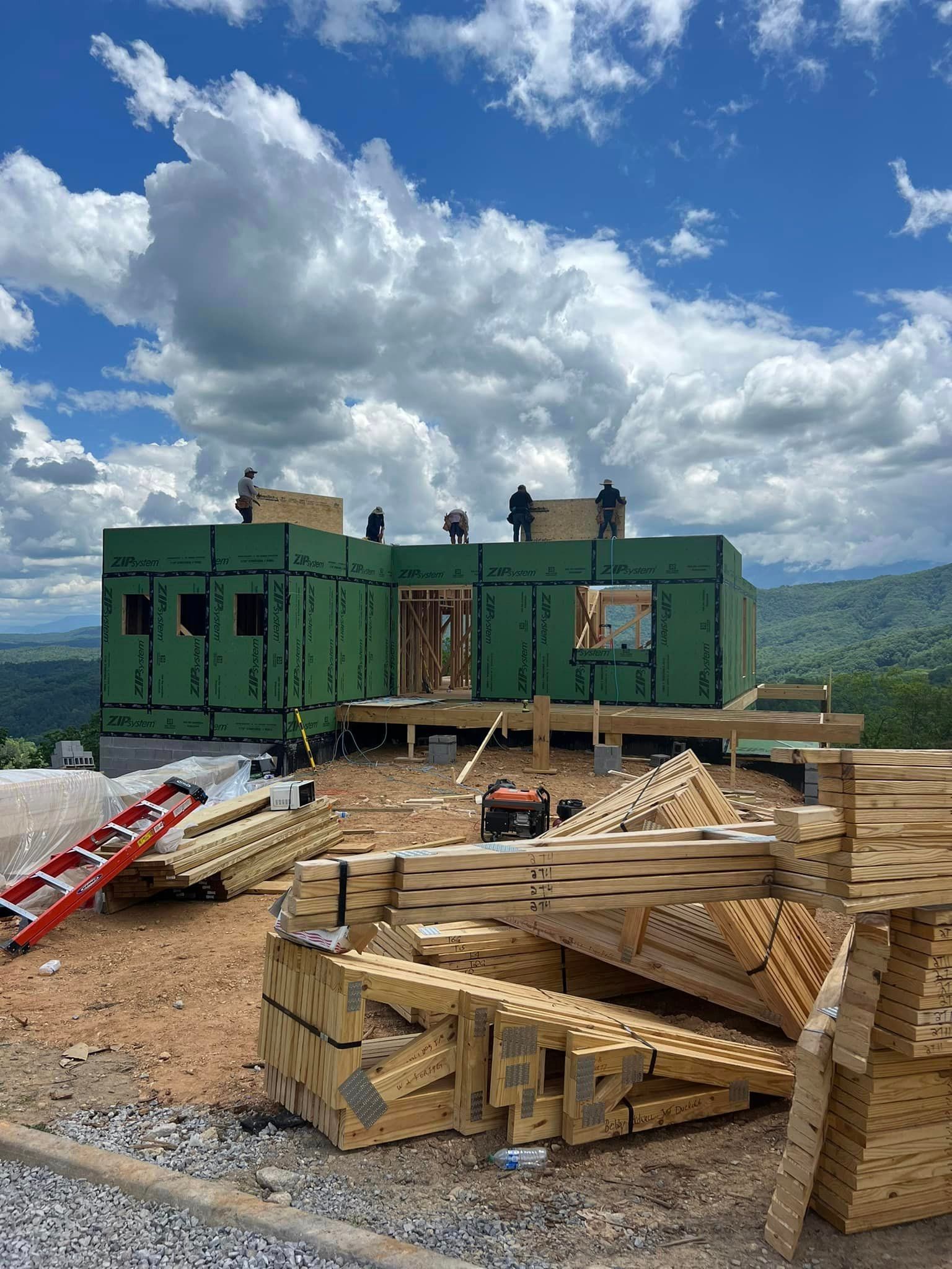 A house is being built in the mountains with a lot of wood in front of it.