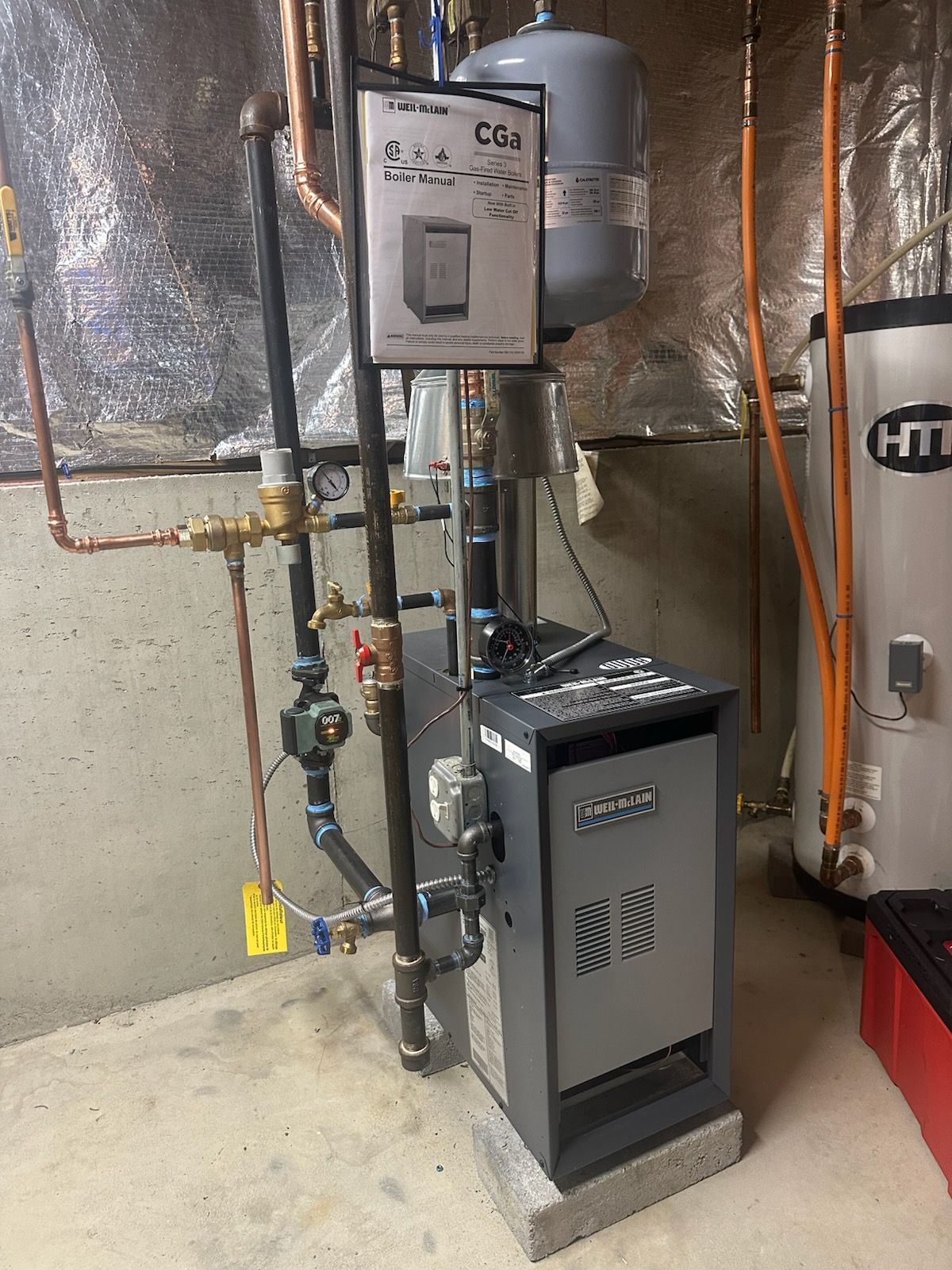 Two wall-mounted air conditioners on a weathered building facade above a barred window