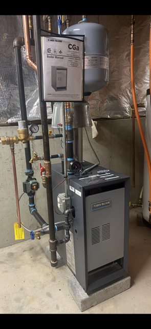 Basement utility room with a gray furnace, water heater, and exposed piping against insulated walls