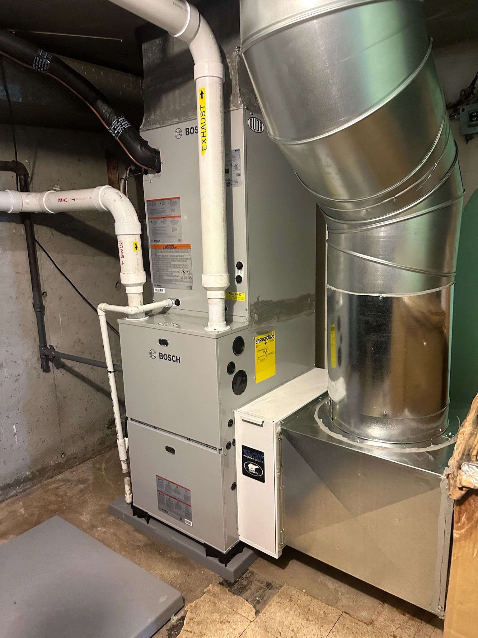 Basement HVAC furnace and metal ductwork beside a silver ventilation unit