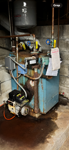 Blue industrial machine with motor, pipes, and a hanging sheet of paper in a dim workshop