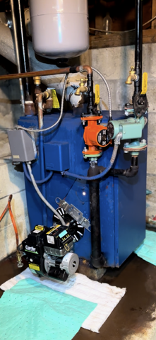 Blue industrial water heater with pipes and valves in a basement utility room