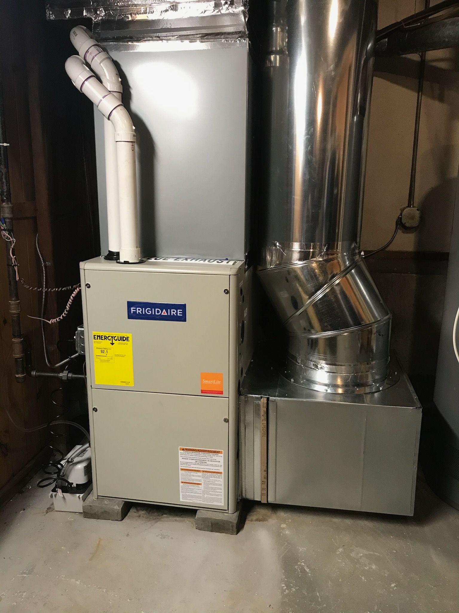 HVAC furnace and ductwork in a basement utility area, with metal vents and beige equipment