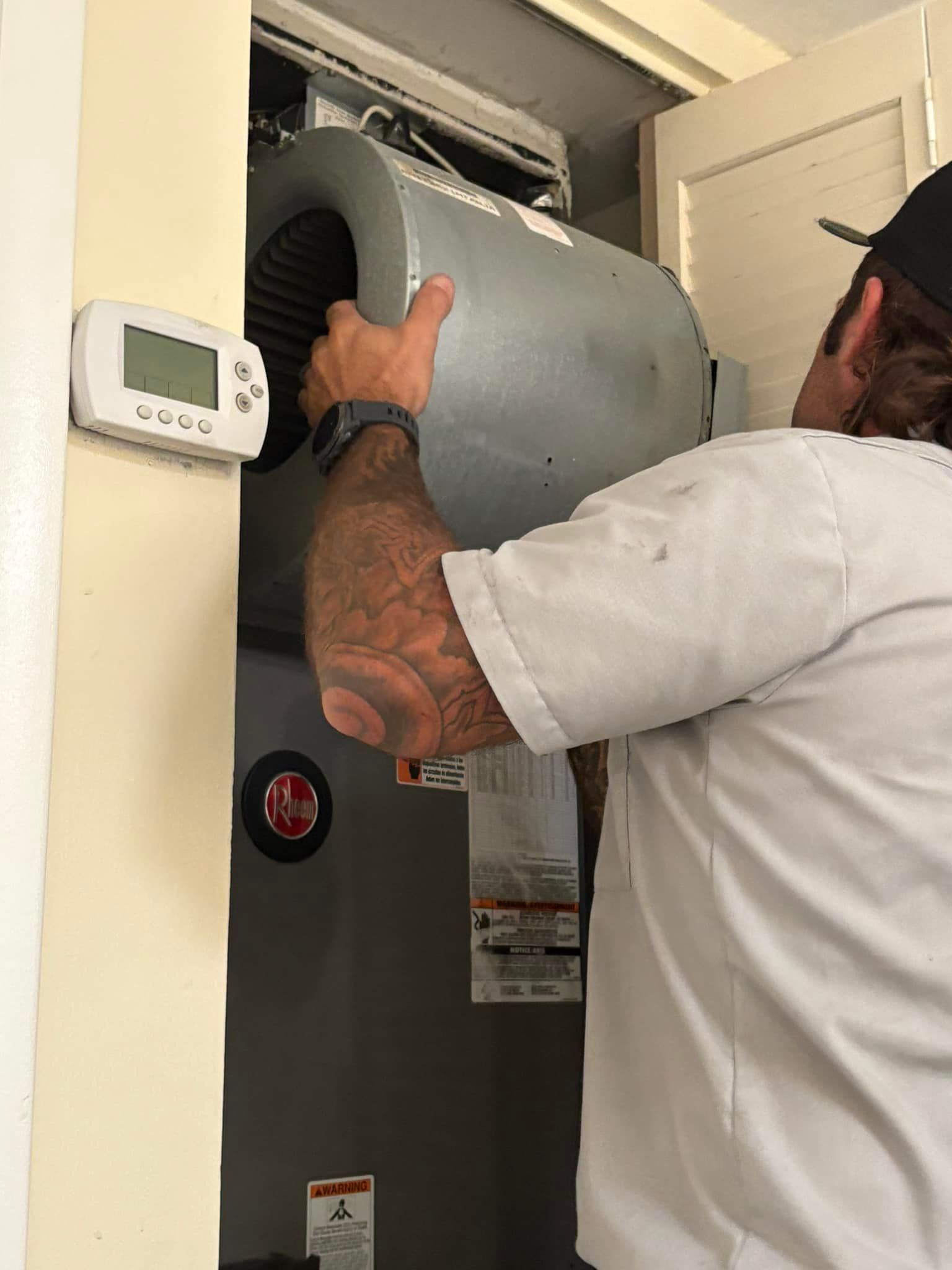 Local Guy technician is working on an air conditioner in a room.