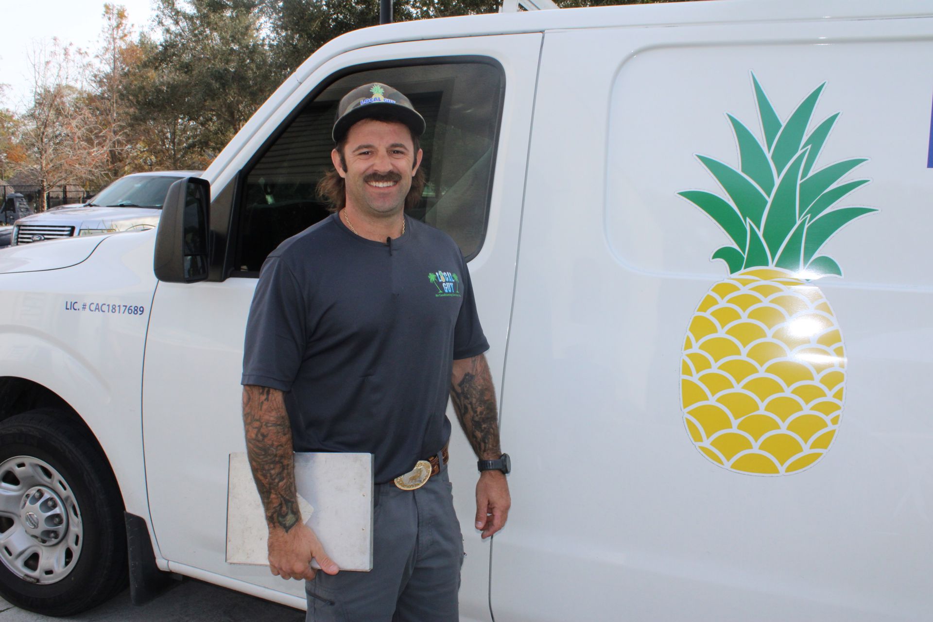 A Local Guy technician is standing in front of a white van with a pineapple on the side.