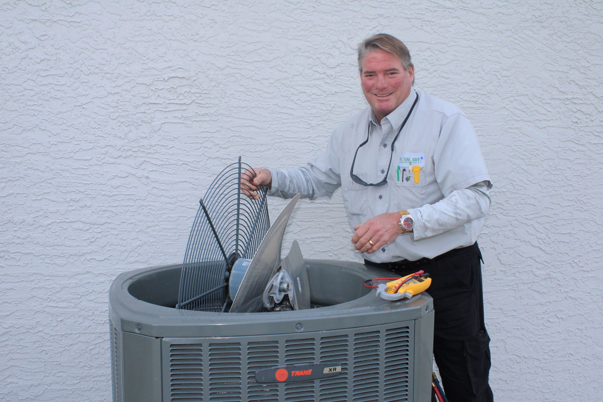 A Local Guy technician is standing next to a large air conditioner.