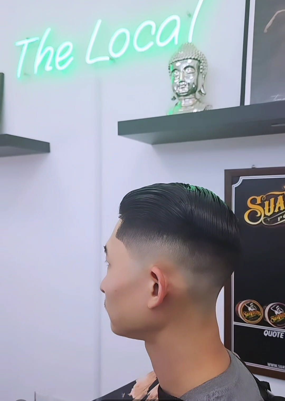 A person with a sharp fade haircut stands in a barbershop labeled 