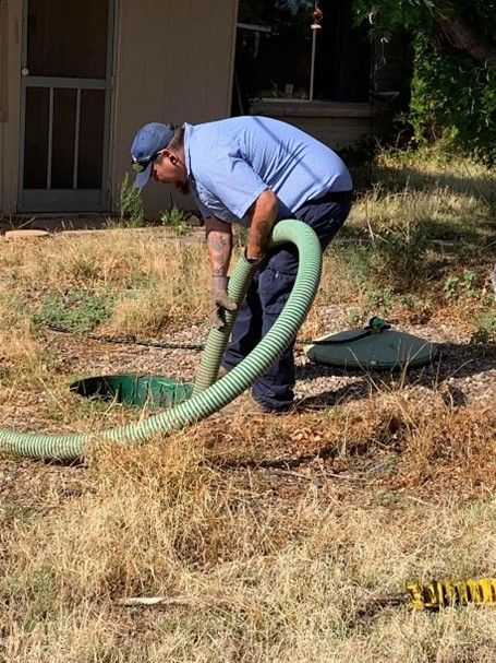 Septic tank truck with hose connected to residential septic tank.