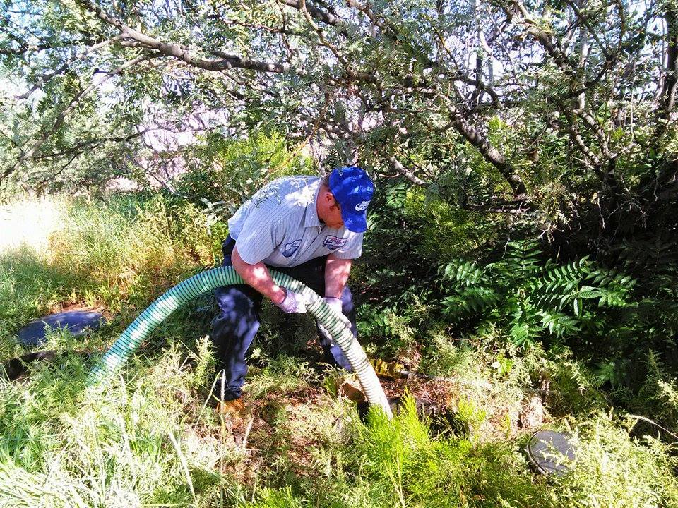 A man is pumping water from a hose in the grass.