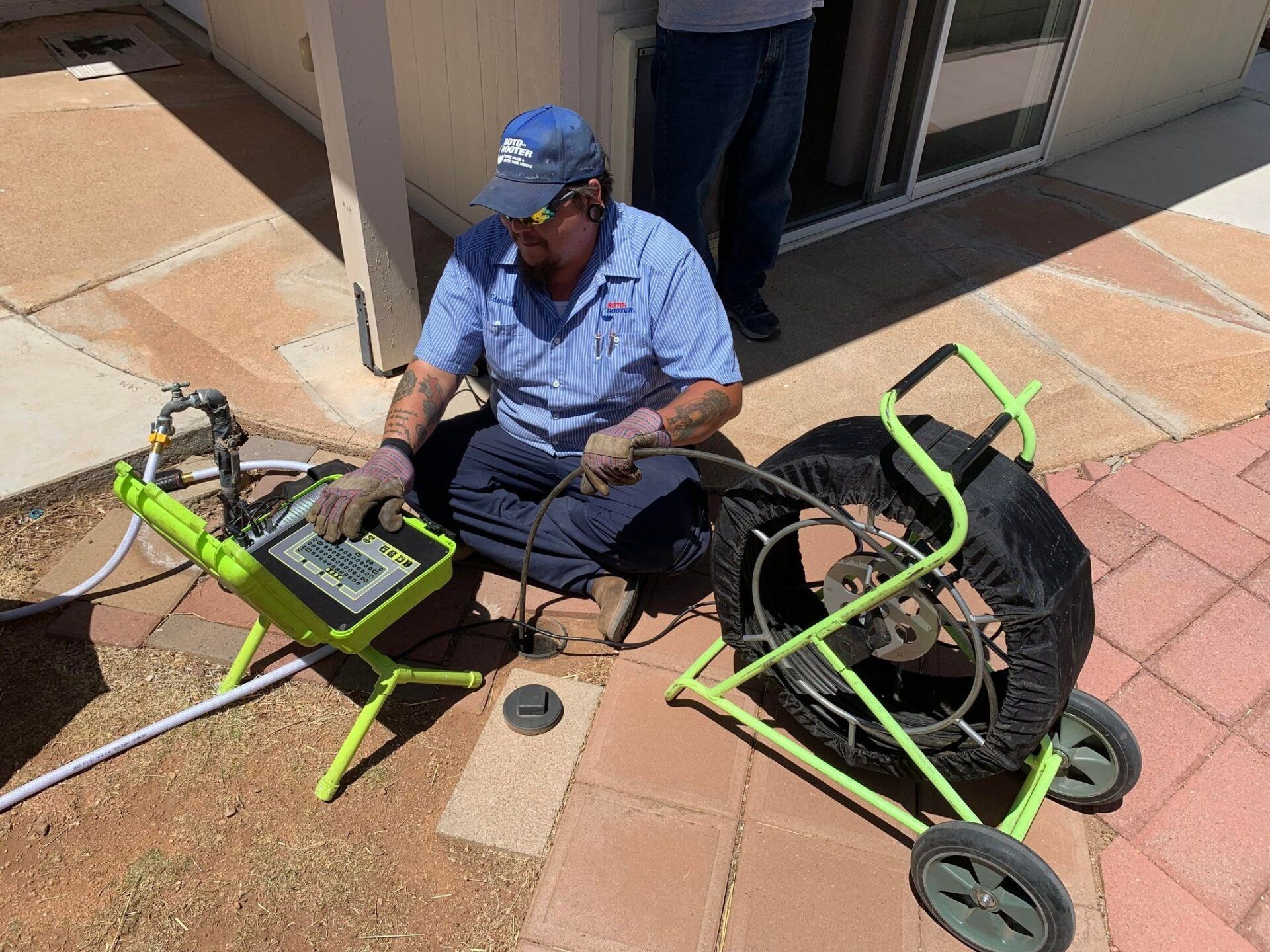A man is sitting on the ground using a drain camera.