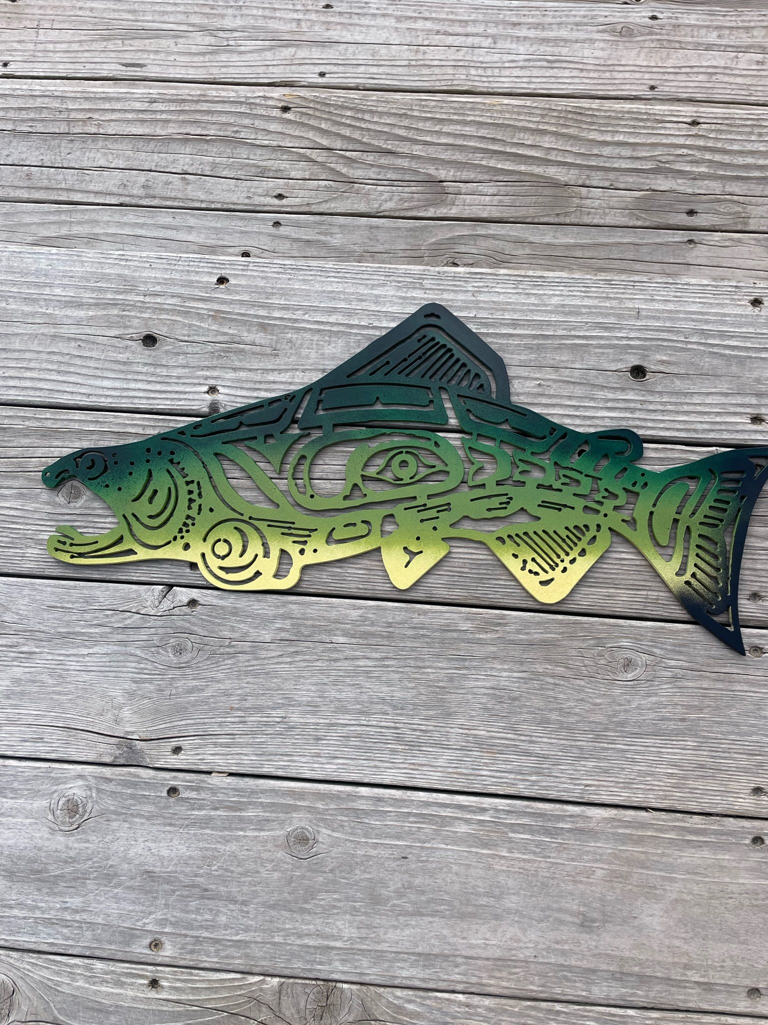 A green and yellow fish is sitting on a wooden table.
