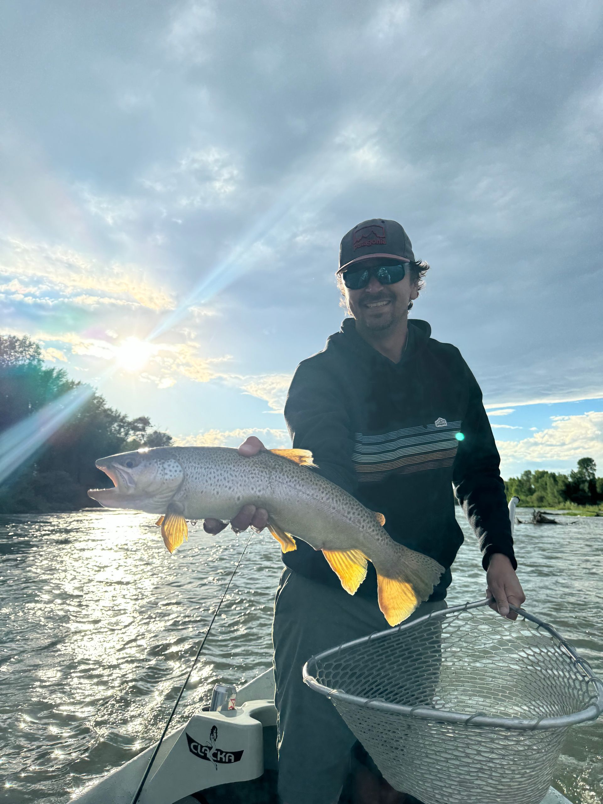 A man in a boat is holding a large fish in his hands.