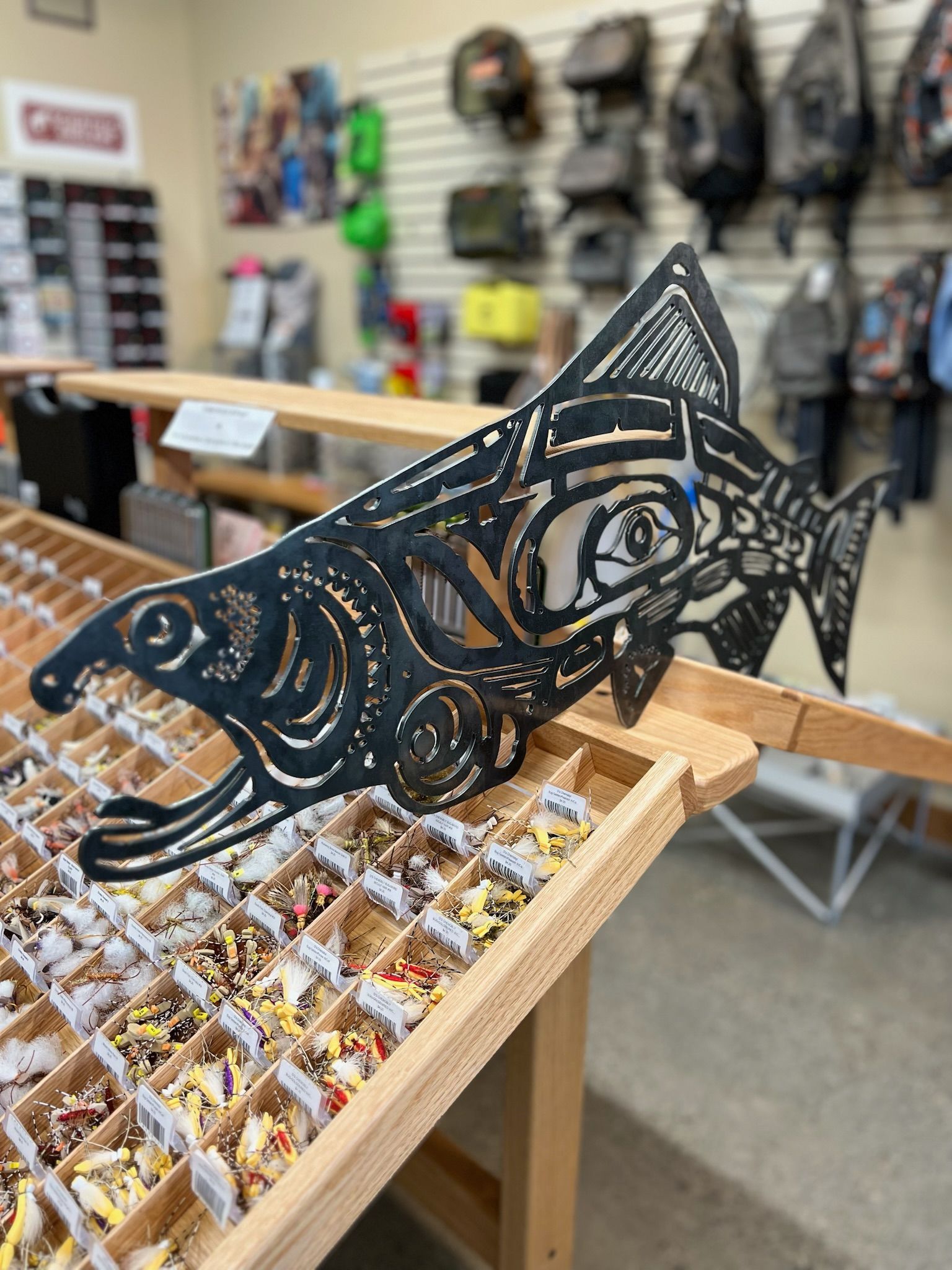 A metal fish is sitting on top of a wooden table in a store.