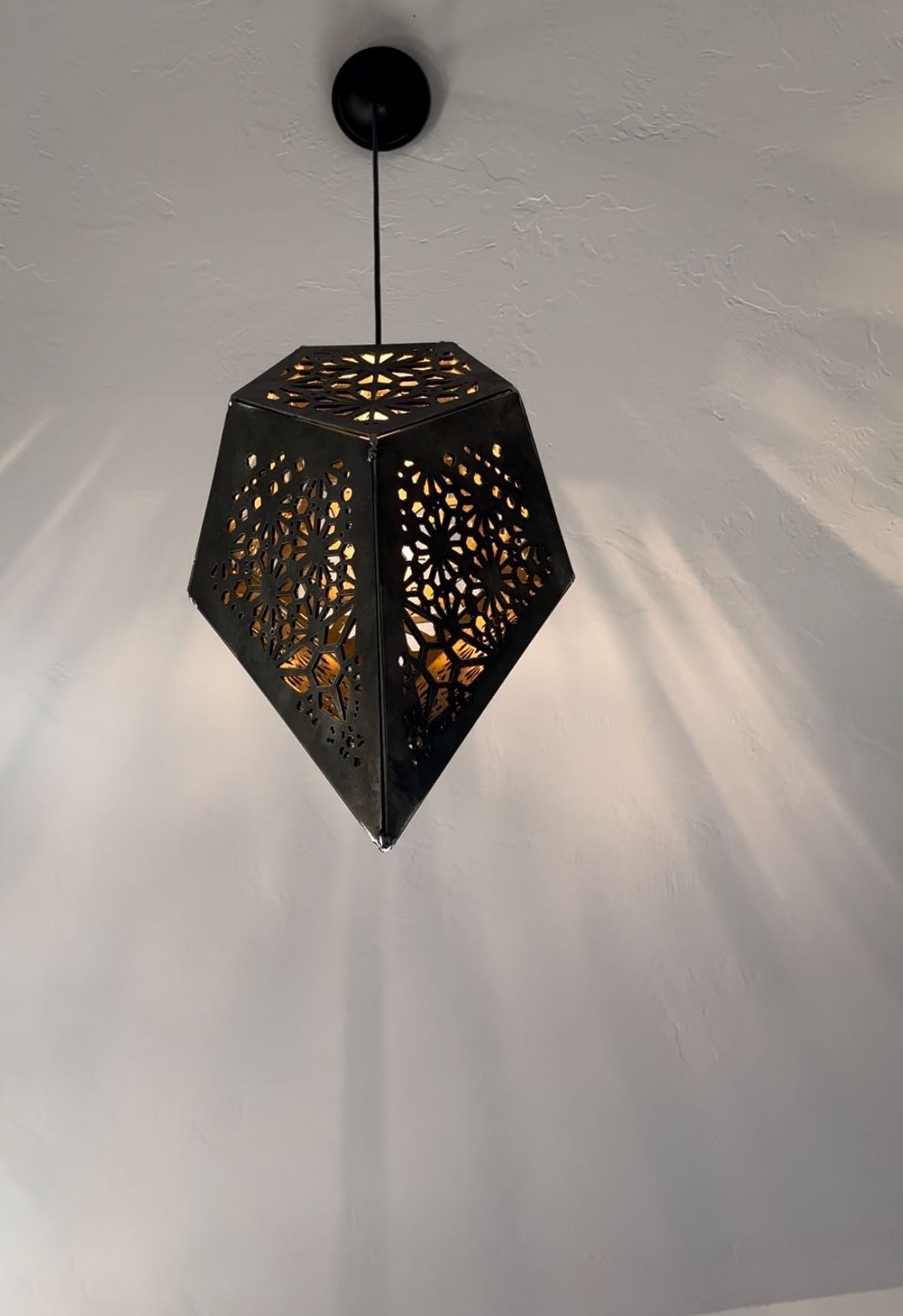 A light hanging from the ceiling with a diamond shaped shade