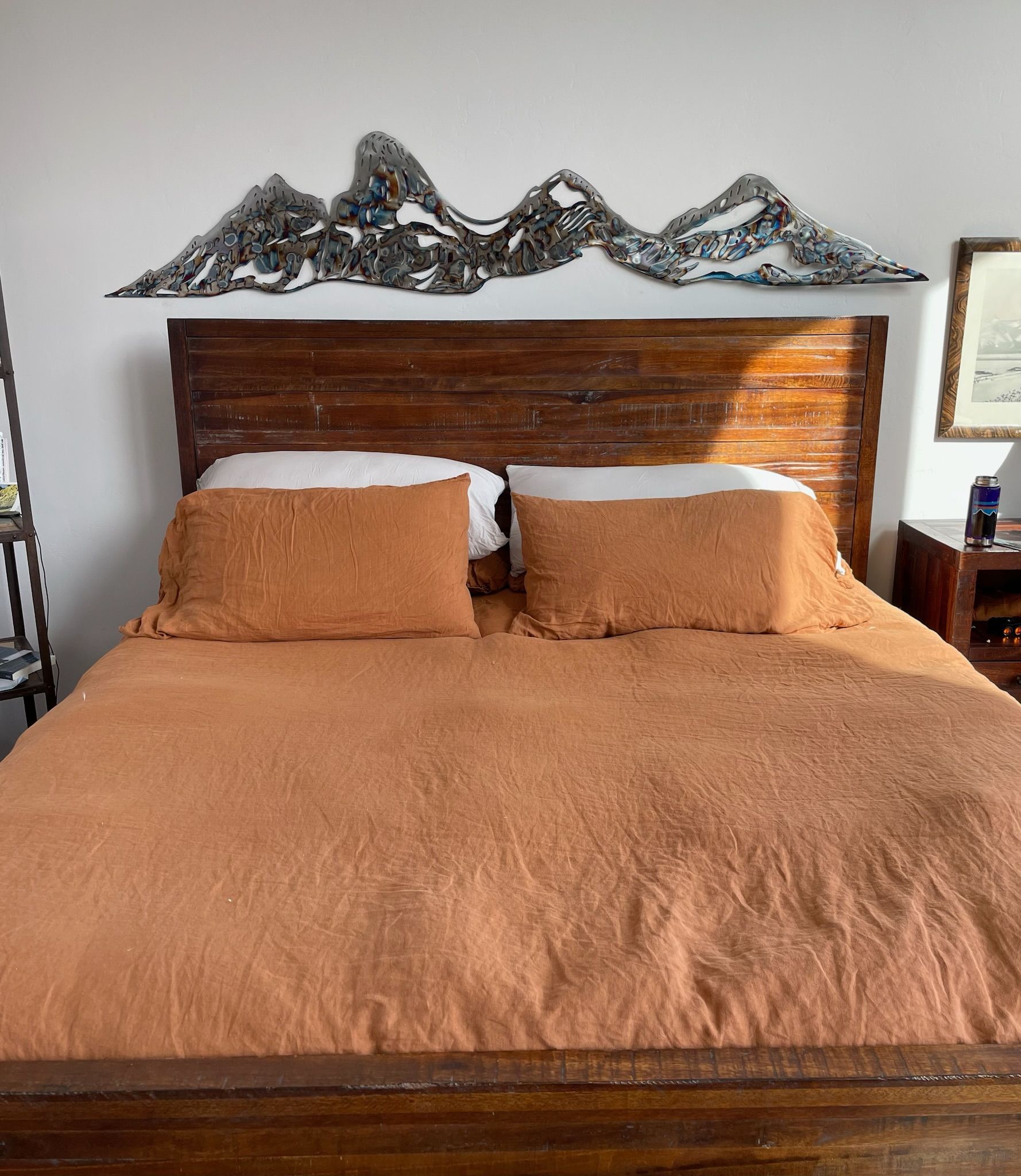 A bed with a wooden headboard and pillows in a bedroom.