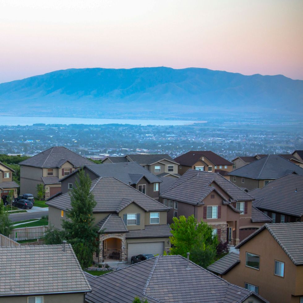 Houses in a suburban neighborhood with a mountain and lake in the background at dusk.