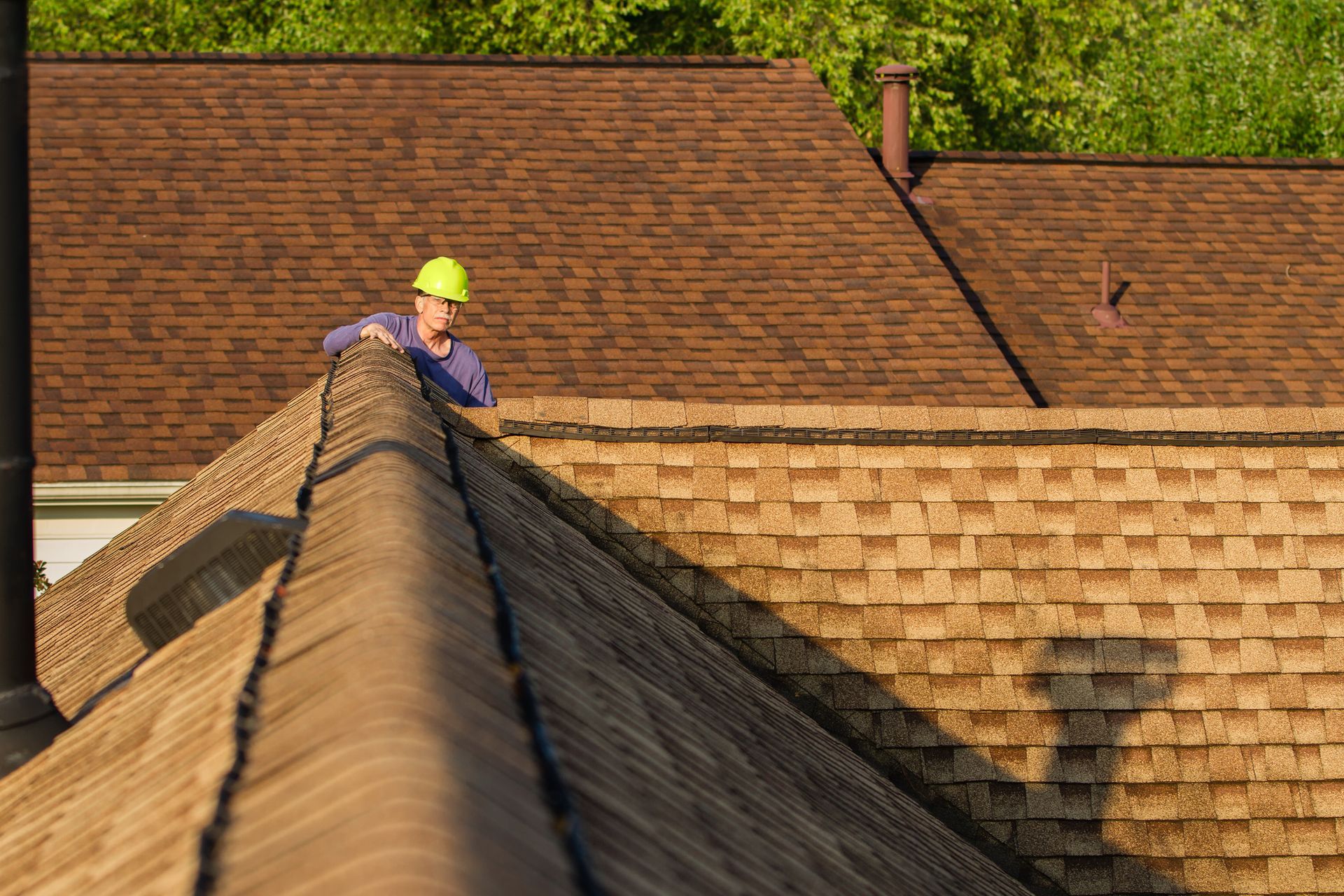 Overhead view of a house with a roof partially under construction; workers, trees, and ladder visible.