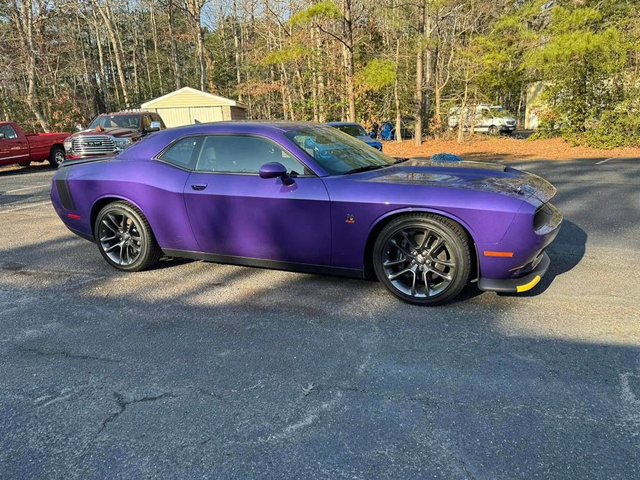 A purple dodge challenger is parked in a parking lot.