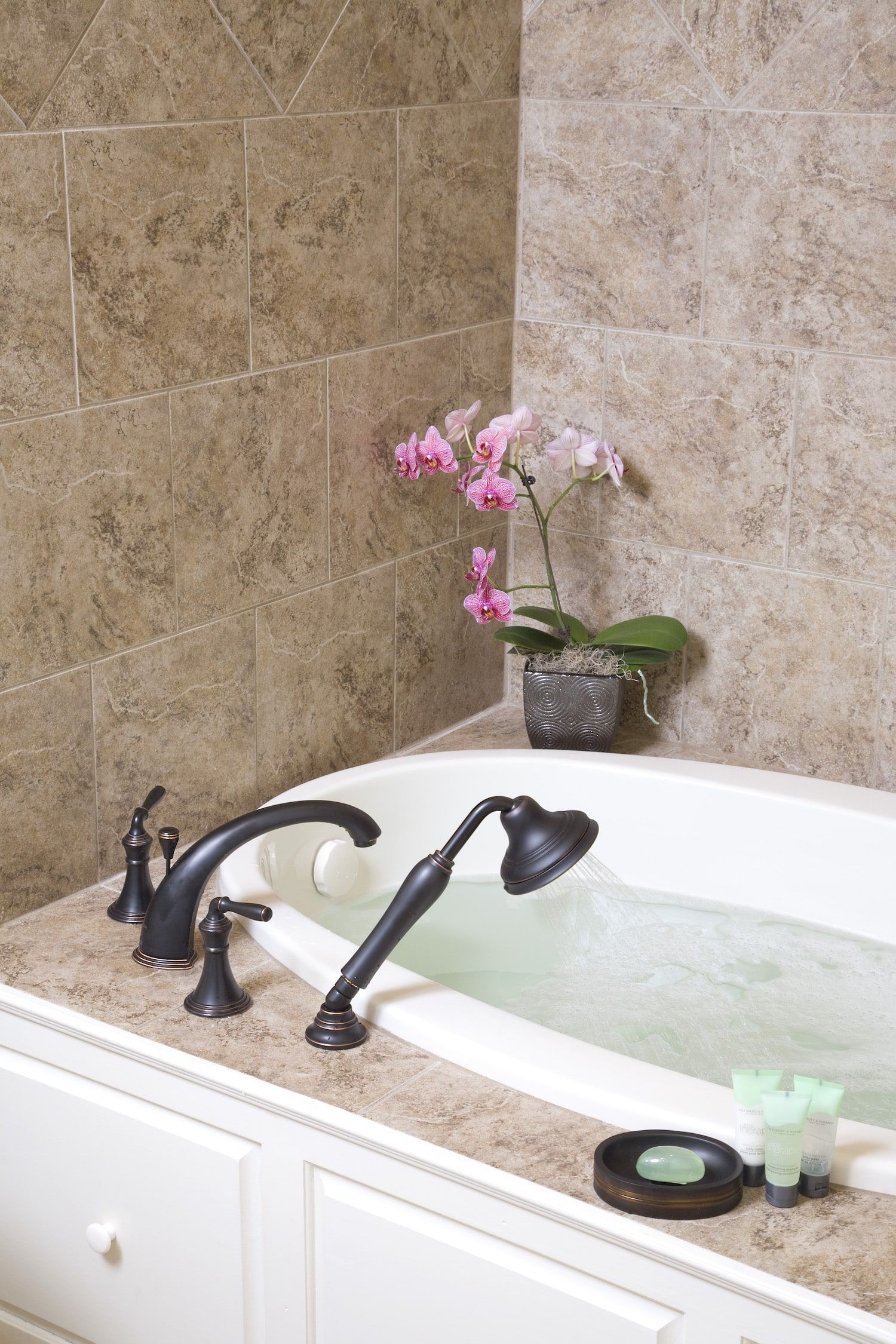 A bathtub with a shower head and a flower in the background.