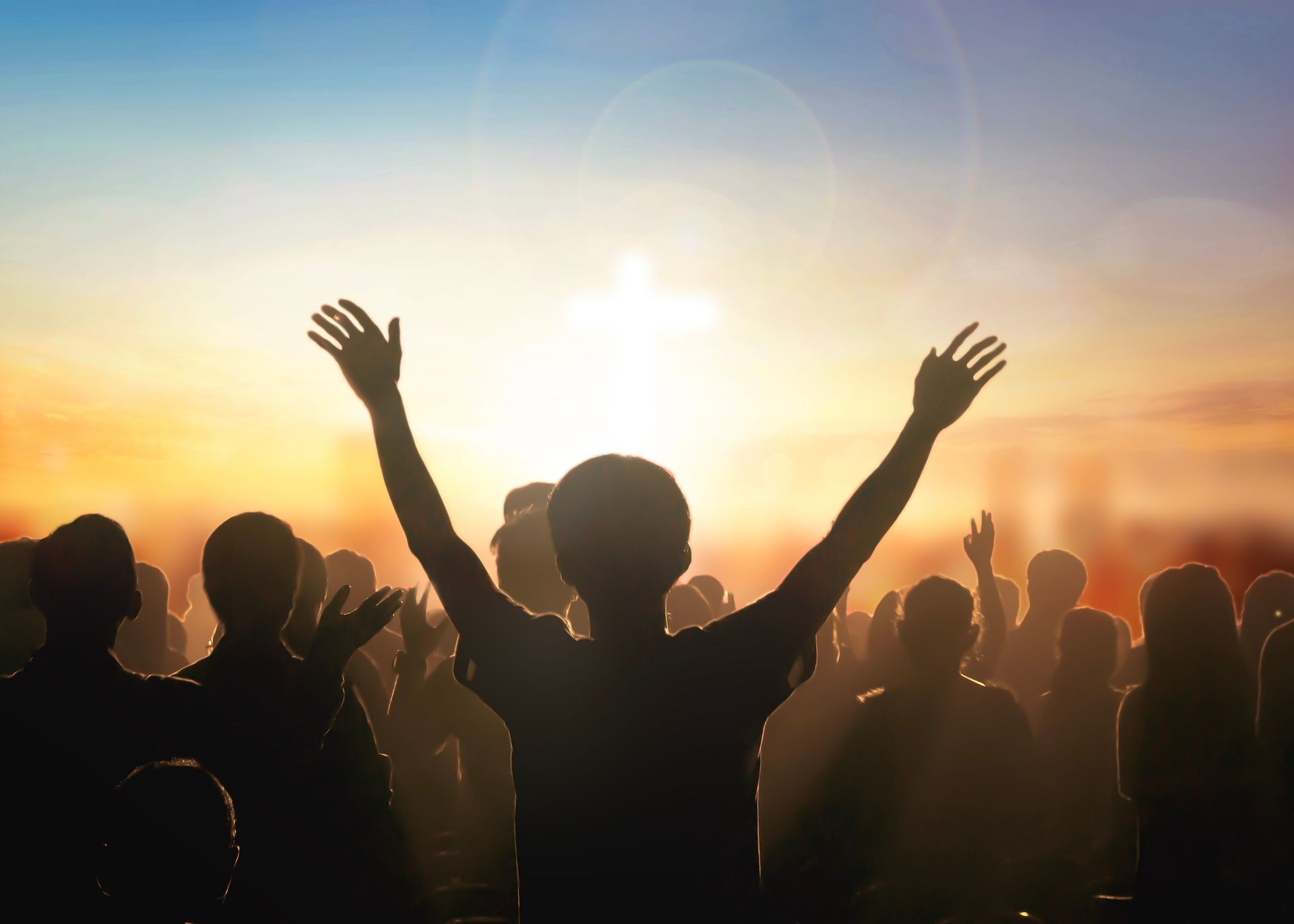 A group of people are standing in a crowd with their arms in the air.