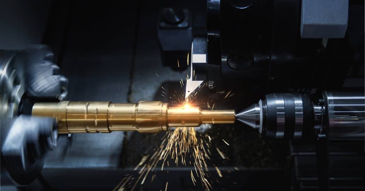 A CNC machine spinning a piece of metal with sparks coming off of it as it cuts the piece into an even shape.