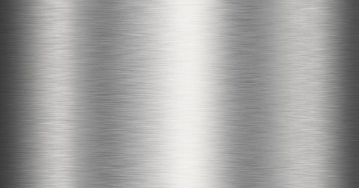 A close-up of a stainless steel surface with a brushed finish. Light reflects from the surface and is brightest in the center.