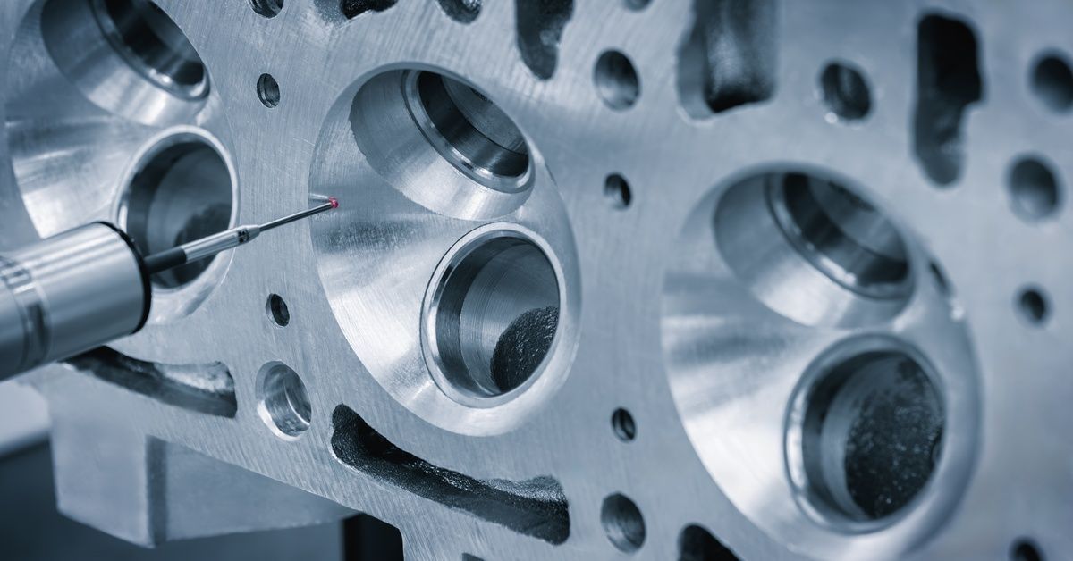 A close-up of a quality-control tool inside a CNC machine with a small red point measuring the surface of a complex metal part.