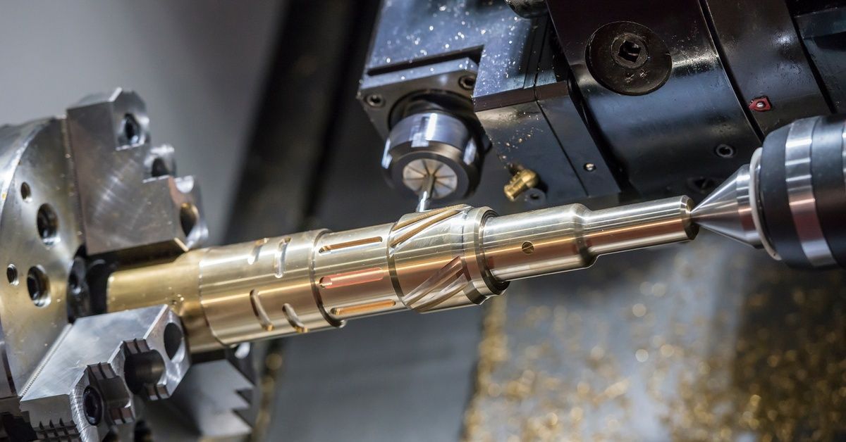 A CNC lathe machine spinning a brass component, removing the material.