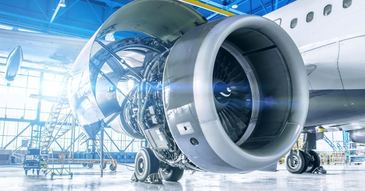 An airplane is in a large hangar with bright light shining through.