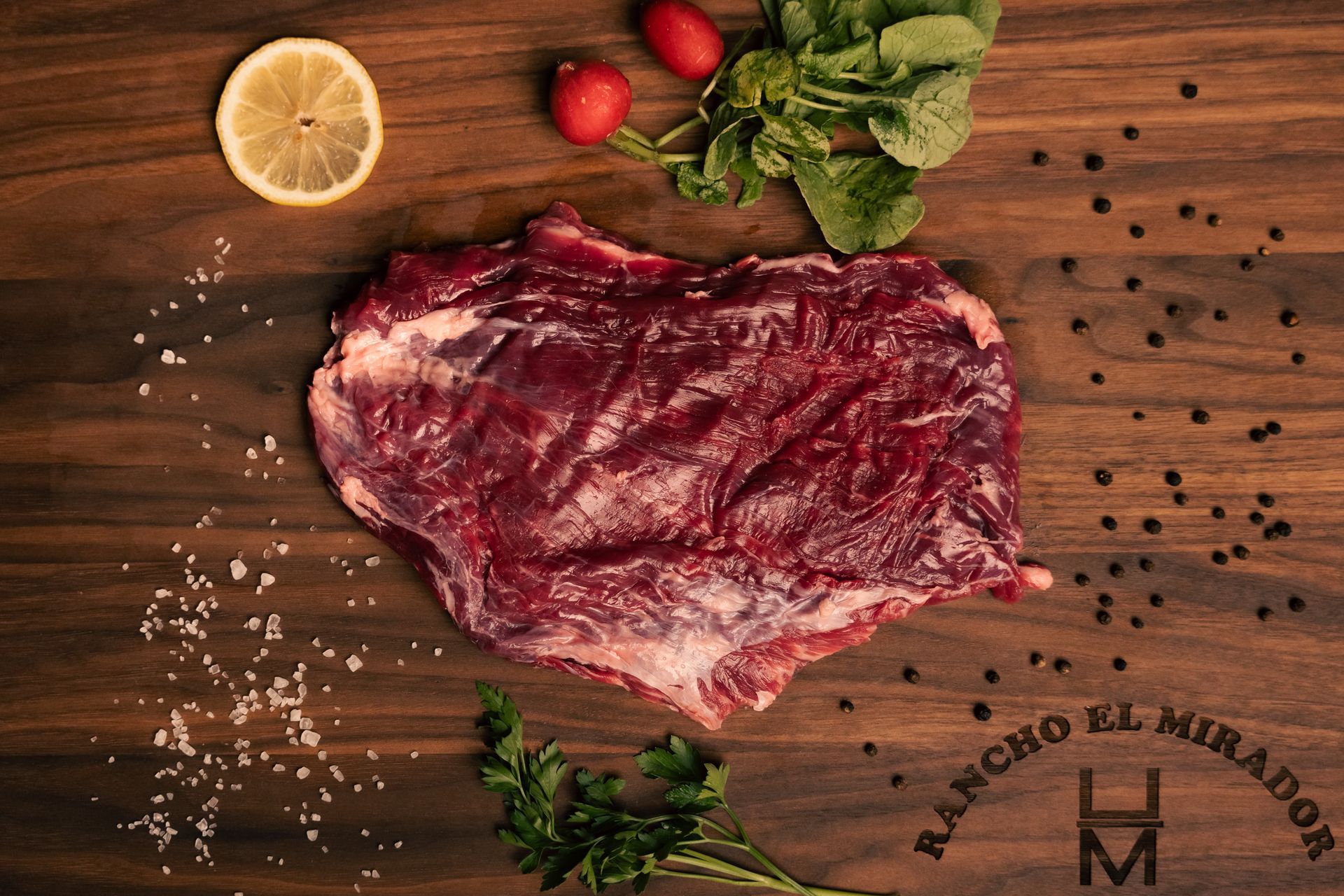 A piece of raw meat is sitting on top of a wooden cutting board.