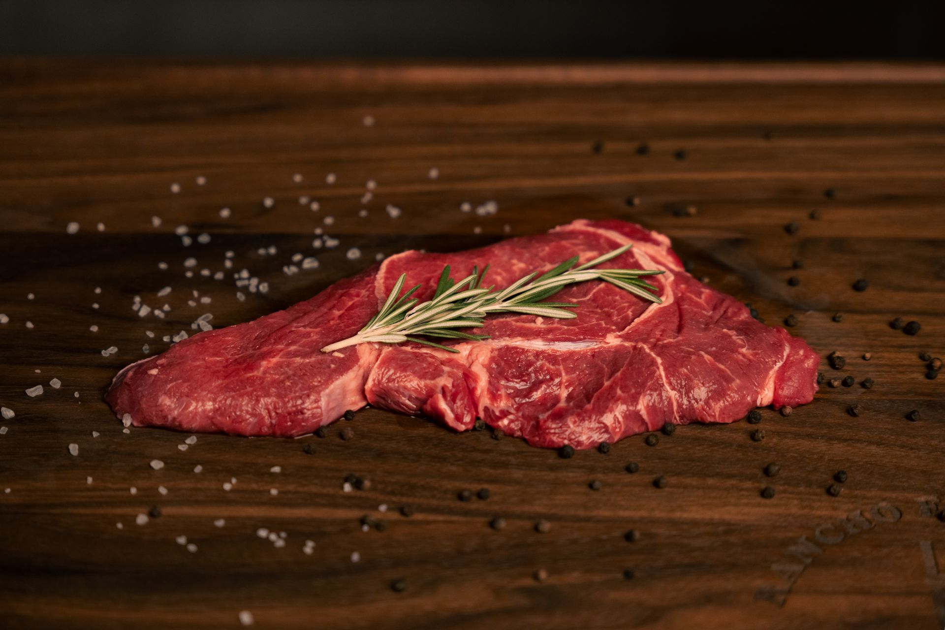 A piece of raw meat is on a wooden cutting board.