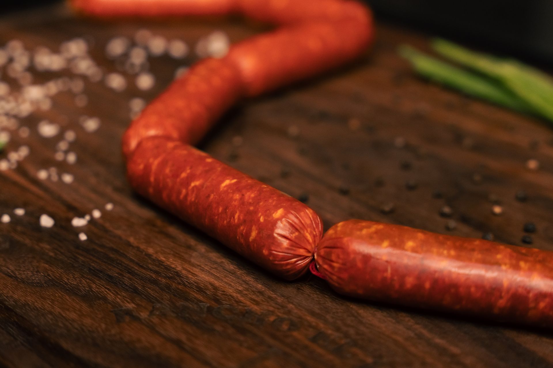 A wooden cutting board with sausages and onions on it