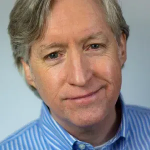 A man in a blue and white striped shirt is smiling for the camera.