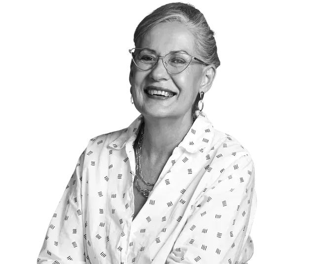 Woman with glasses, smiling, wearing a patterned shirt.