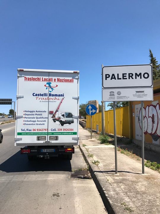 Un camion bianco è parcheggiato davanti a un cartello di palermo